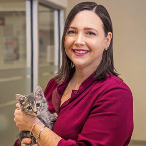 A person, smiling, holding a kitten